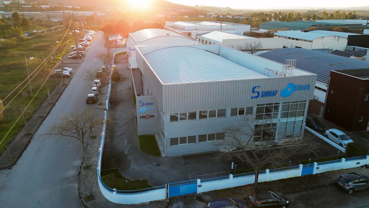 An aerial view of the ImSim building in Taveiro at sunset, with the signs on the facade.